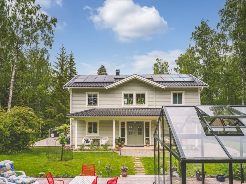 Grått hus med växthus framför.