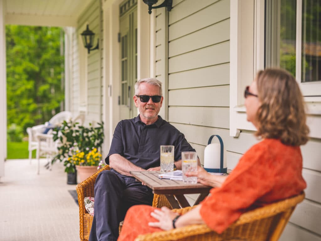 Två personer som sitter och pratar på deras veranda.