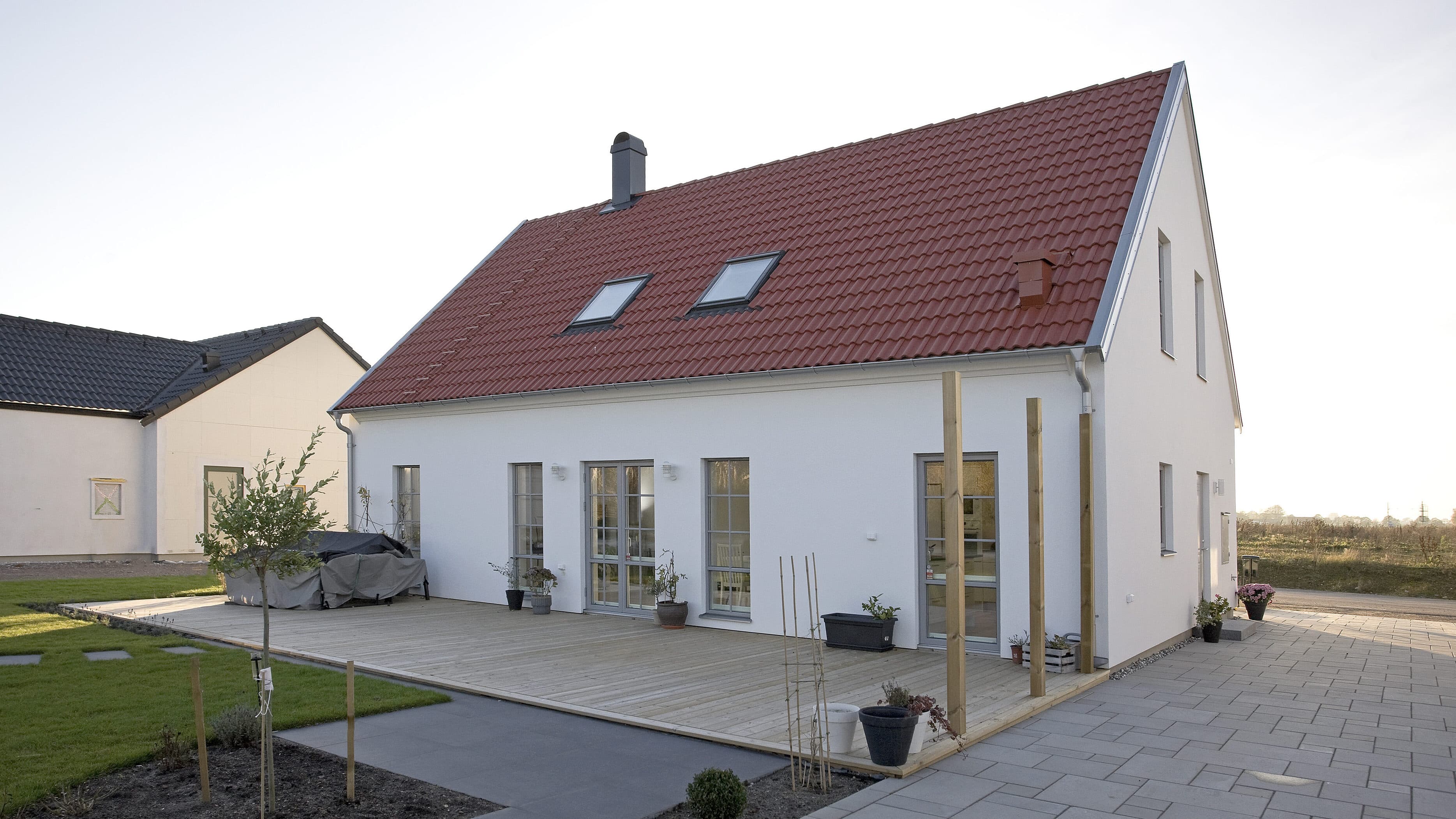 Bild på ett hus med vit puts och rött tak. 